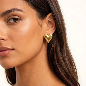Polished 18K gold heart-shaped stainless steel earrings worn by a model in a close-up