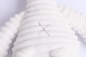 Macro shot of white corduroy plush rabbit belly with brown cross-stitched detail