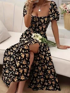 Detail of floral maxi dress featuring high slit hem and summer pattern on black fabric