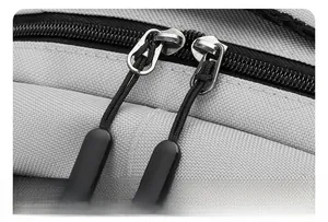 Macro detail of smooth dual zippers with black pull cords on grey textured backpack fabric