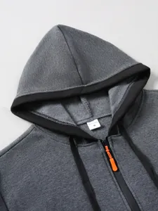 Gros plan détaillé du sweat gris foncé avec zip orange et étiquette de col