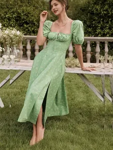 Green floral summer dress with puff sleeves and side slit shown in a garden setting
