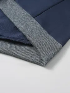 Détail des coutures contrastées et poignets côtelés sur sweat à capuche bleu et gris