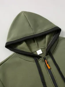 Gros plan du sweat à capuche vert olive avec fermeture éclair noire et tirette orange