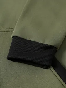 Détail macro du sweat à capuche vert olive avec poignets côtelés noirs et texture de tissu