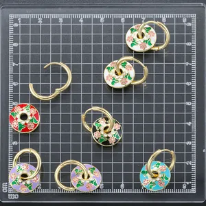 Detailed view of colorful enamel flower charms on golden hoop earrings in various colors