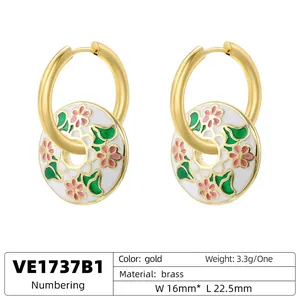 Vintage gold hoop earrings with white enamel flower charm and green leaf accents