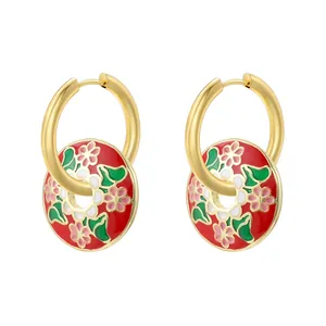 Detail of gold hoops with red enamel floral pendants featuring pink flowers and green leaves