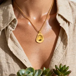 Golden cowboy hat pendant on delicate link chain worn by model in soft sunlight