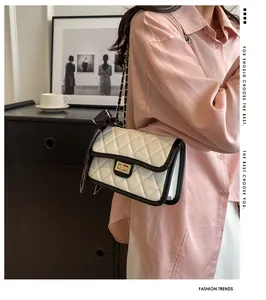 Detail of white quilted crossbody bag with gold lock and decorative silk scarf