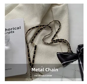 Detail of elegant gold hardware chain strap with a stylish black and white ribbon bow