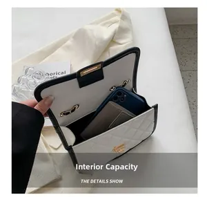 Internal capacity detail of white quilted crossbody bag with black trim and phone