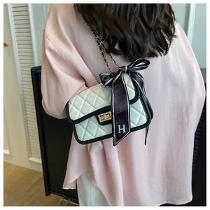Close-up of a white quilted crossbody bag with black trim and a decorative H-logo ribbon