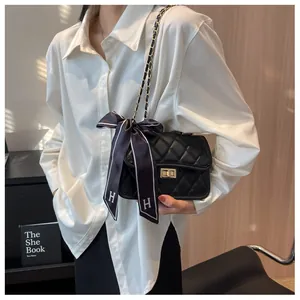 Close-up of black quilted crossbody bag with gold twist lock and silk scarf detail