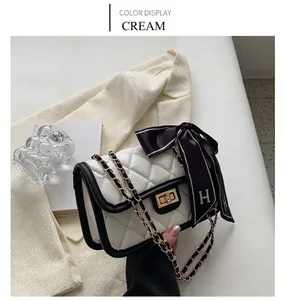 Detail of off-white quilted chain bag with elegant silk scarf and golden twist lock