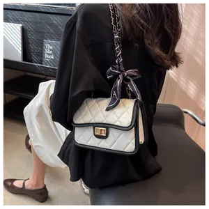 Detail of quilted crossbody bag with gold chain and silk scarf on a model's shoulder