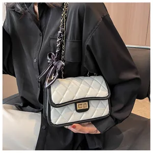 Detail view of quilted shoulder bag featuring gold twist lock and silk scarf handle