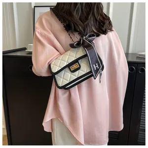 Close-up of white quilted chain bag with silk scarf on a stylish woman's shoulder