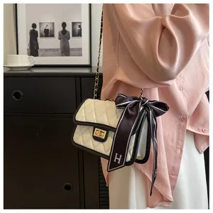 Close-up of white quilted crossbody bag with black trim and silk scarf detail