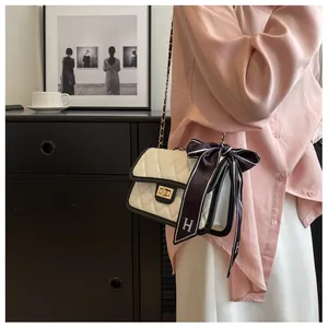 Close-up of quilted chain bag with gold rotary clasp and decorative striped silk scarf