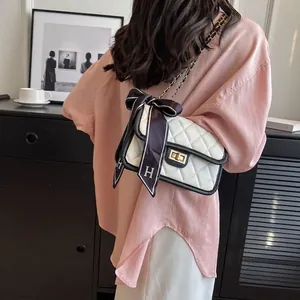 Quilted white crossbody bag with black piping and gold hardware and silk bow strap