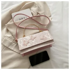 Close-up of pink leather crossbody bag with 3D butterfly embroidery and gold handle