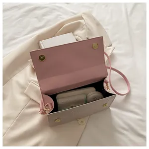 Detail of white shoulder bag showing pink interior with magnetic closure and daily essentials
