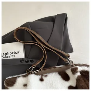 Nahaufnahme der flauschigen Schultertasche mit Kuhmuster und Lederriemen aus Pelzimitat