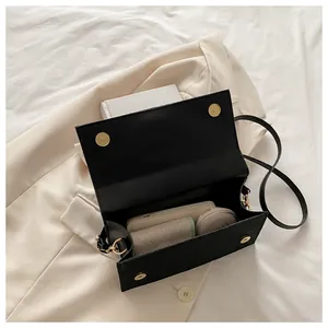 Detail of black leather square bag interior holding power bank and cosmetics