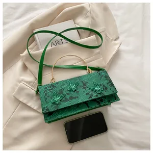 Close-up of bright green lace crossbody bag with embroidered 3D butterfly details