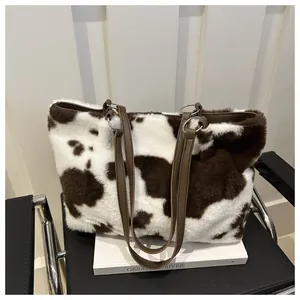 Nahaufnahme der Plüsch-Tasche mit Kuhmuster, Lederriemen und Metallringen