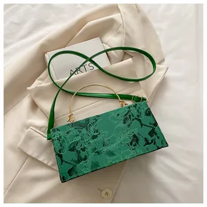 Close-up of green marble pattern bag with gold metal handle on a beige blazer