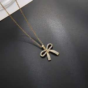 Elegante goldene Schleifenkette mit Zirkon-Mikropave auf schlichtem dunklem Grund