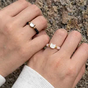 Detail of beaded cat rings featuring white shell charms and golden metal accents