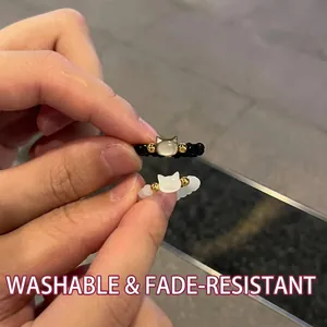 Detail of black and translucent white cat beaded rings with gold accents on fingers