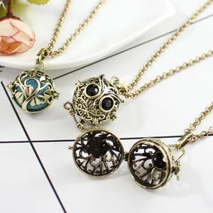 Vintage bronze hollow locket necklace with owl pendant and diffuser ball on white plate