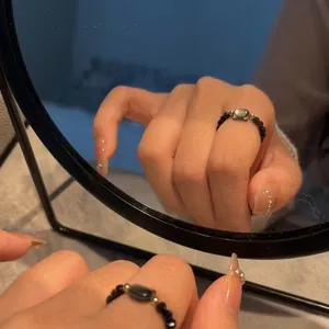 Close-up of beaded ring featuring black pearls and a rectangular moonstone center stone