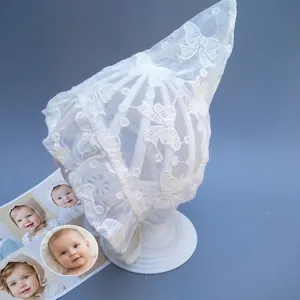Detail of baby lace pixie hat with butterfly embroidery and chin strap on a white stand
