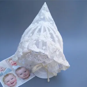Detail of white lace baby bonnet with floral embroidery and silk chin strap on a stand