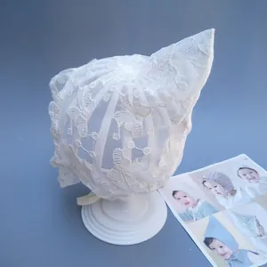 Macro shot of white floral lace embroidery on a pointed baby princess bonnet