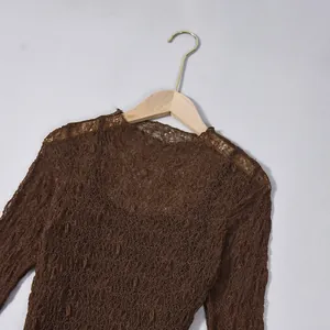 Detailed close-up of coffee brown sheer floral lace fabric and round neckline texture