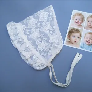 Detailed view of delicate white lace baby bonnet with intricate floral embroidery