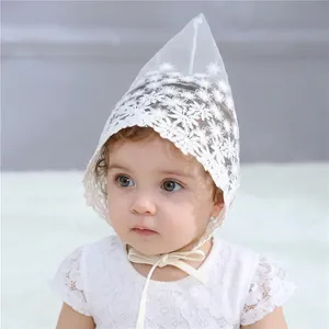 Detailed view of white floral lace baby bonnet with scalloped edges and tie string