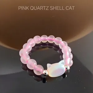 Close-up of beaded ring with rose quartz beads and shell cat head pendant charm