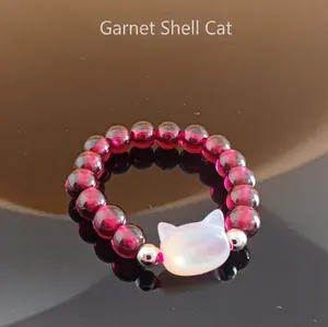 Macro shot of garnet beaded ring featuring a white shell cat head and silver accents