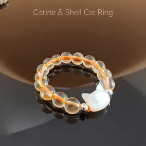 Macro shot of citrine beads and white shell cat head charm on an elastic ring