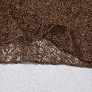Detail shot of sheer dark brown lace fabric with intricate floral crochet patterns