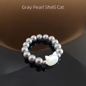 Close-up of grey pearl beaded ring with white shell cat head and reflective finish