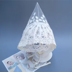 Detail of white lace baby bonnet featuring daisy floral embroidery and lace trim