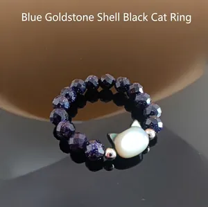 Macro shot of blue sandstone beaded ring featuring a white shell cat charm and silver beads